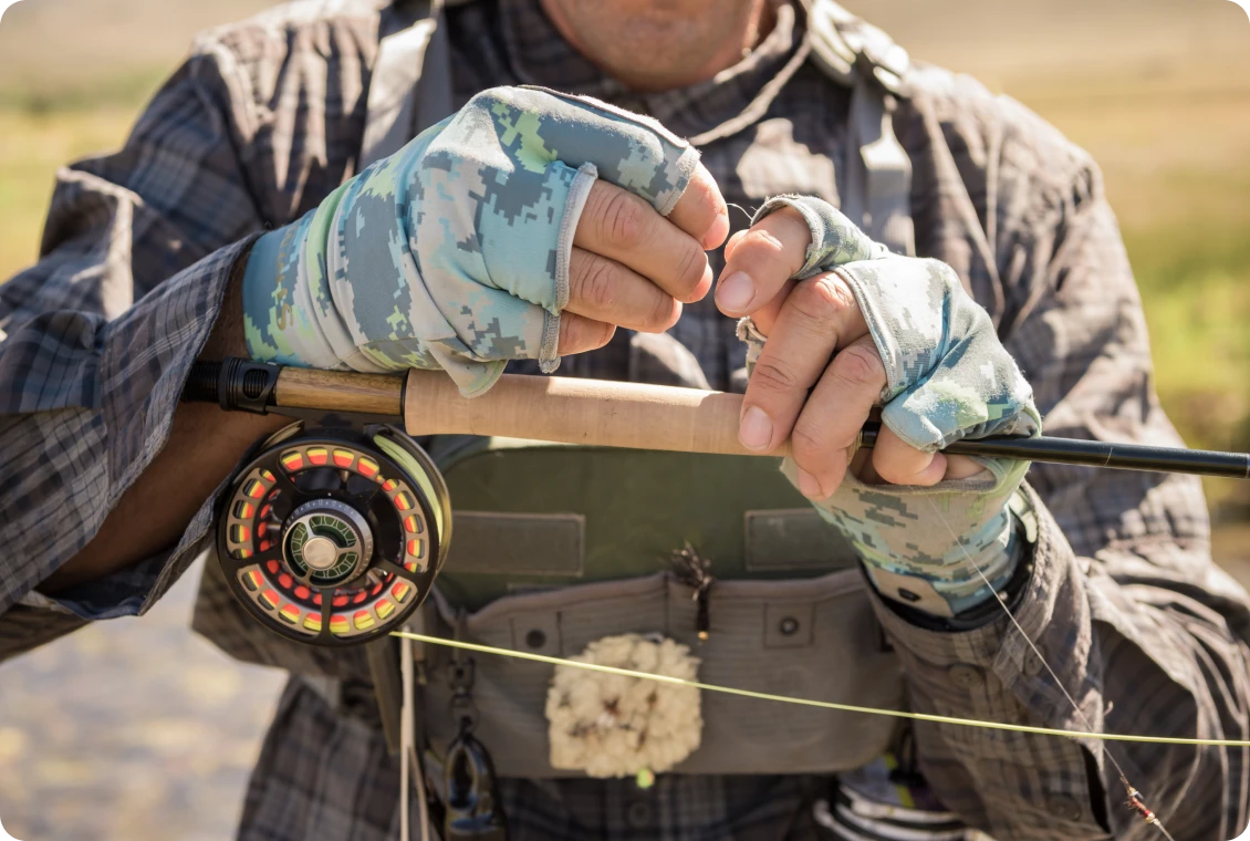 Fisherman adjusting fishing reel outdoors