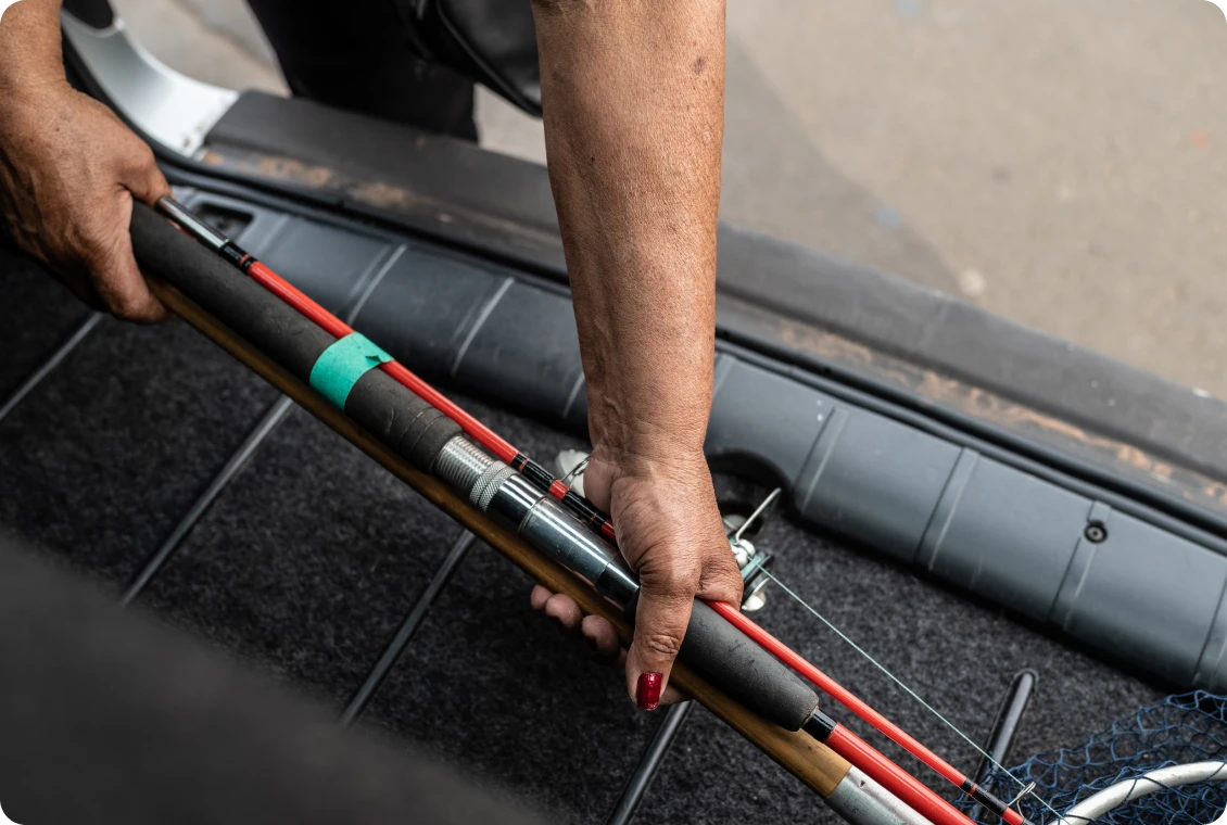 Hands organizing fishing gear in vehicle